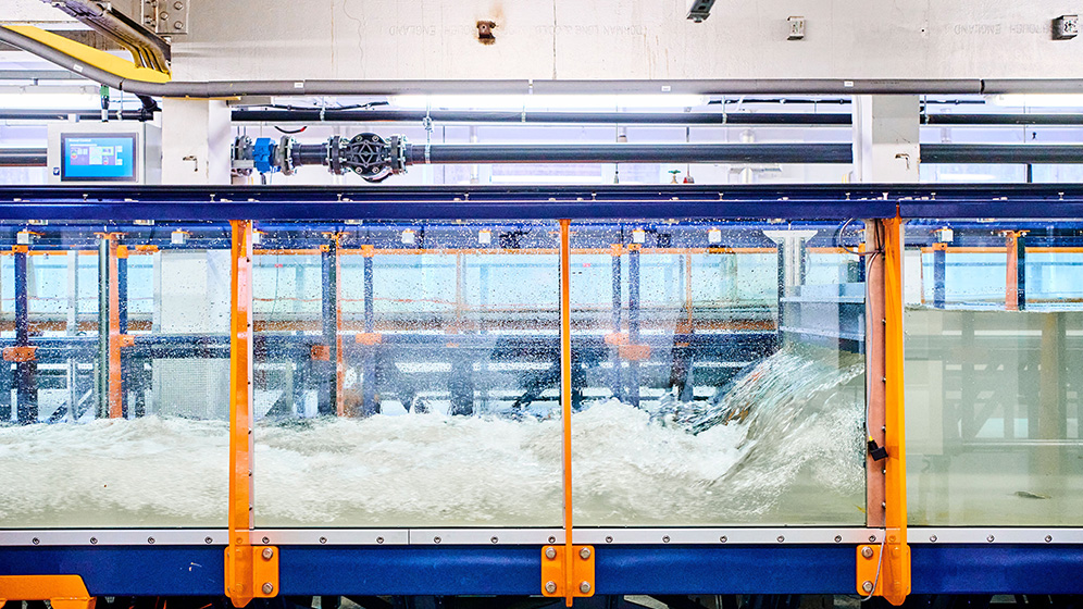 Two students and an academic using a piece of equipment to test the strength of a concrete beam.