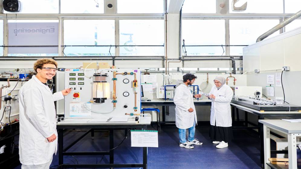 Several students wearing lab coats while working in a laboratory.