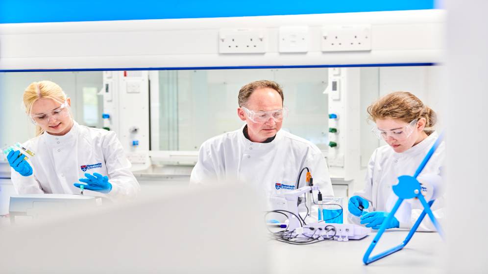 Two students and a staff member working in a laboratory.