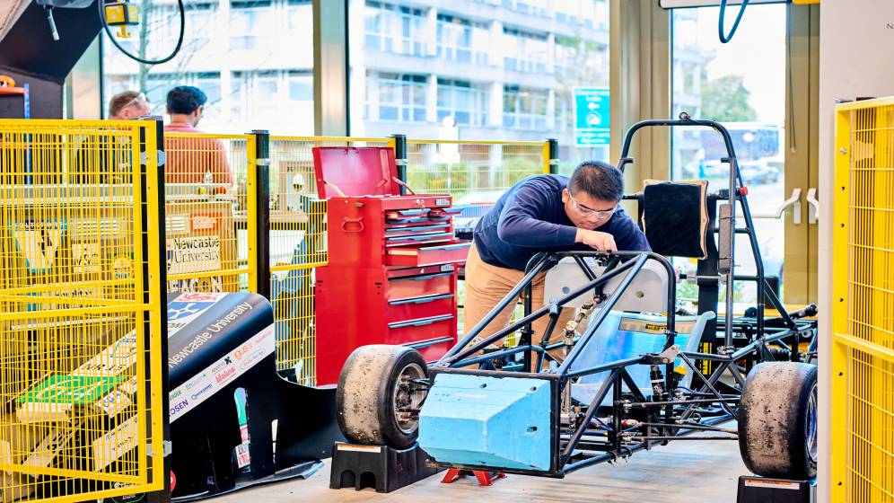 A male student working on a racing car chassis.