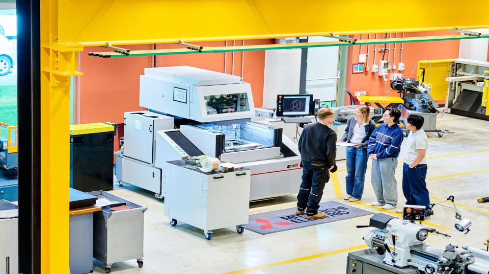 A technician and a group of students inspecting a piece of equipment.